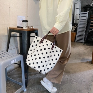 Detail of French retro polka dot canvas tote bag with brown leather handles and rivets