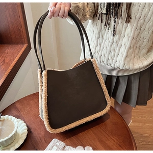 Detail of plush lamb wool trim on dark brown tote bag in a warm cafe setting