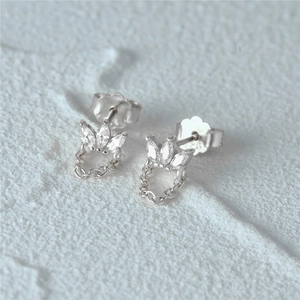 Macro detail of silver crown stud earring with sparkling zircon and chain tassels