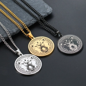 Close-up of wolf head pendant necklaces in silver, gold, and black with Greek key patterns