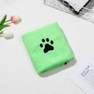 Close-up of soft green coral fleece pet towel with black paw print embroidery detail