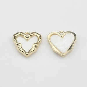 Detail of two gold-plated heart charms with hollow design and white shell inlay