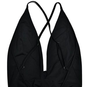 Detail of black V-neck bodysuit showing thin cross-back straps and metal ring accents