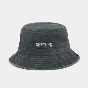 Macro shot of embroidered white NEWYORK logo on dark grey washed cotton bucket hat