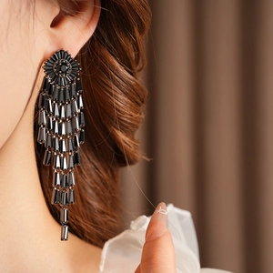 Close-up of elegant long black crystal tassel earrings worn for an evening formal look