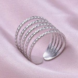Macro shot of silver multilayer open ring with beaded textures on pink silk background