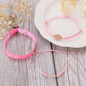 Detail of pink WWJD cross bracelets set with LOVE letter patterns and golden charms