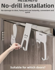 Macro detail of white cat-shaped over-the-door hooks installed on a dark wood door