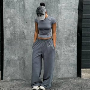 Ensemble de sport gris avec t-shirt cintré et pantalon large dans un décor industriel