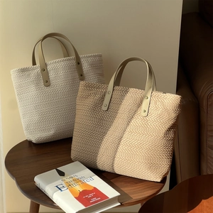 Detail of woven straw tote bag texture with V-shaped pattern and leather handles