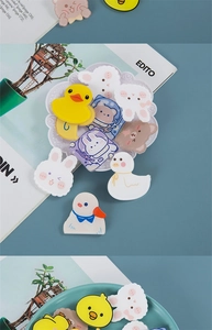 Detailed view of cute duck and bear acrylic pins on a decorative ceramic plate
