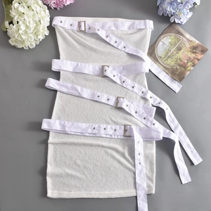Flat lay of a white tube knit dress featuring four buckled straps and a sleek urban style