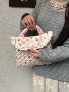 Close-up of quilted laptop bag with bear print and delicate white lace trim detail