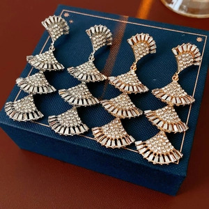 Macro shot of gold and silver fan-shaped fringe earrings with inlaid crystal rhinestones
