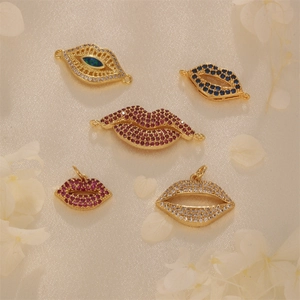 Golden lip and eye jewelry pendants with colorful cubic zirconia on beige fabric