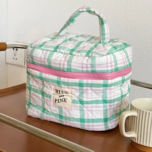 Detailed view of quilted cotton cosmetic bag featuring green plaid pattern and logo label