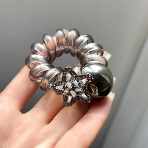 Detail shot of a grey spiral hair tie featuring a sparkling rhinestone star charm