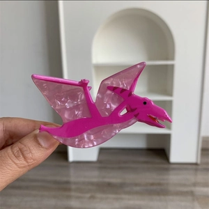 Detailed view of a pink pterosaur-shaped acrylic hair claw with a pearly marble texture