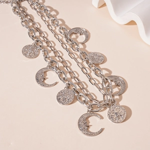 Detail of silver layered necklace with crescent moon and sun face pendants in retro style
