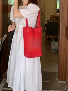 Detail of red canvas tote bag featuring white Happy Happy Happy lettering on shoulder strap