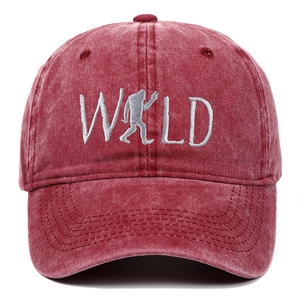 Detailed close-up of white WILD embroidery with sasquatch on washed burgundy baseball cap