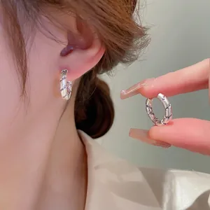 Silver hoop earrings with purple spiral zircon accents and a floral cat eye stone design