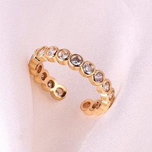 Detailed close-up of adjustable 18k gold plated ring with white cubic zirconia on pink silk