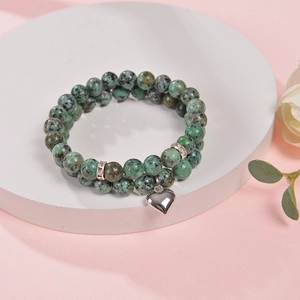 Detail of double-layer beaded bracelet with green zebra stones and heart pendant
