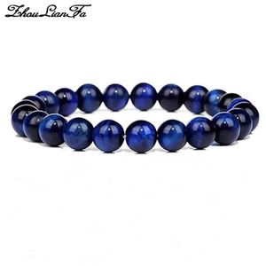 Macro shot of dark blue cat-eye stone bracelet featuring glossy round beads on white base