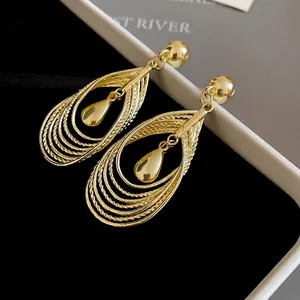 Exaggerated multi-layer hollow teardrop pendant earrings in golden finish on black velvet