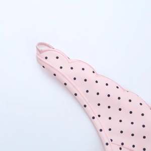 Detail shot of pink polka dot fabric with scalloped edge stitching and fine knit texture