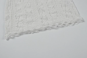 Close-up of white lace dress hem featuring intricate floral embroidery and scalloped edges