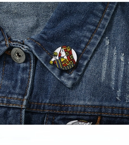 Macro view of Queen of Hearts enamel playing card brooch on blue denim jacket lapel