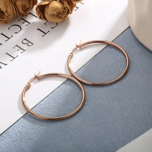 Detail view of large rose gold stainless steel hoop earrings with minimalist design