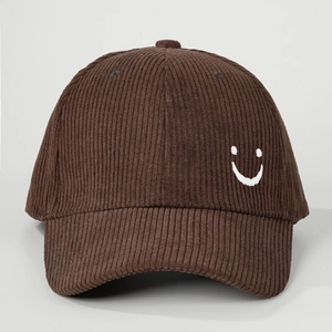 Detailed view of dark brown corduroy texture and white embroidered smiley face on baseball cap