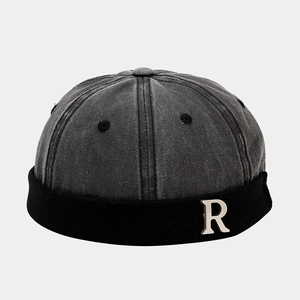 Detail of vintage washed grey miki hat featuring a silver metal R letter emblem on the front