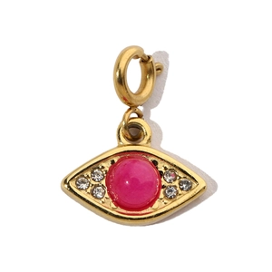Macro detail of gold evil eye pendant with pink gemstone and white cubic zirconia