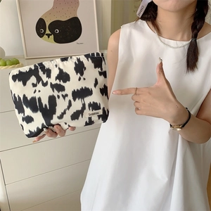 Detail shot of a cow print floral cotton cosmetic bag with a small woven label
