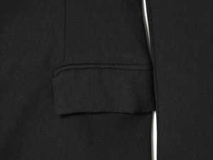 Detailed close-up of the stitching and woven black fabric on a tailored blazer dress