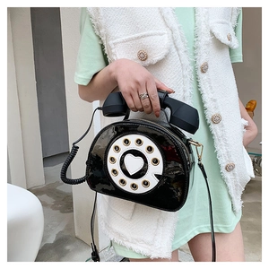 Close-up of retro black telephone-shaped crossbody bag with a heart dial design