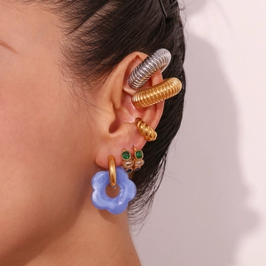 Close-up of blue flower drop earrings and gold ear cuffs set on model ear