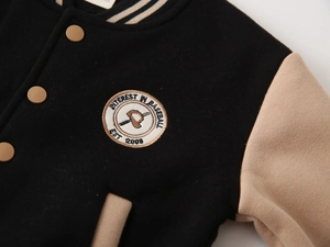Detail of boys' baseball jacket featuring premium embroidery badge and snap buttons