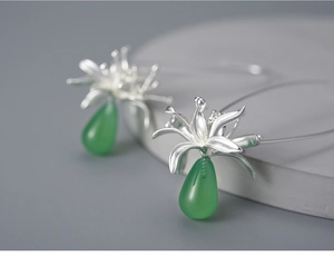 Macro detail of silver floral earring with green teardrop chalcedony pendant