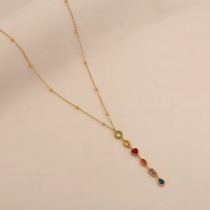 Detail of colorful glass gemstones on a gold Y-shaped necklace with small beads