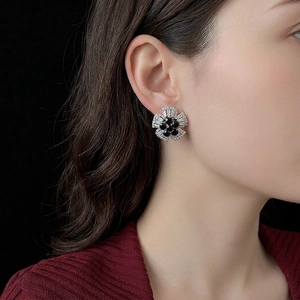 Elegant floral stud earrings with black center and baguette-cut zircons worn by a model