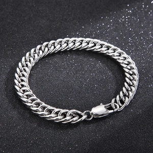 Detailed view of polished silver Cuban link chain bracelet with lobster clasp on dark background