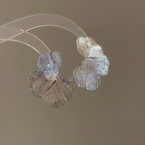 Vue macro de boucles d'oreilles fleur argentée avec texture métal brossé et pétale 3D
