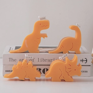 Set of four orange dinosaur scented candles displayed creatively on decorative books