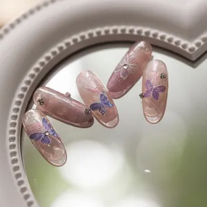 Close-up of 5D nail art stickers featuring purple butterfly patterns and micro rhinestones