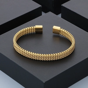 Polished gold stainless steel C-shaped braided open bangle displayed on a black stand